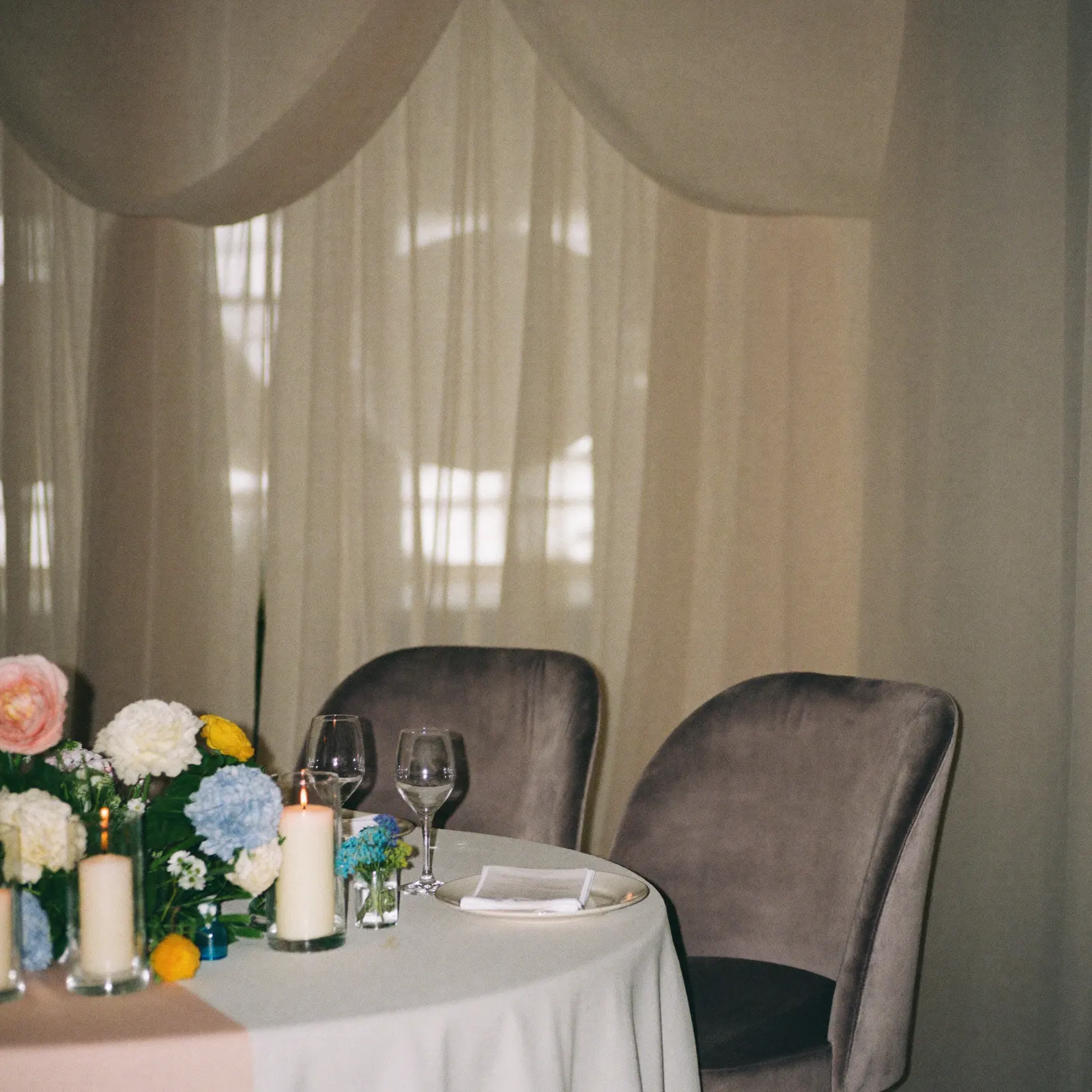 A sweetheart table with velvet chairs and draping