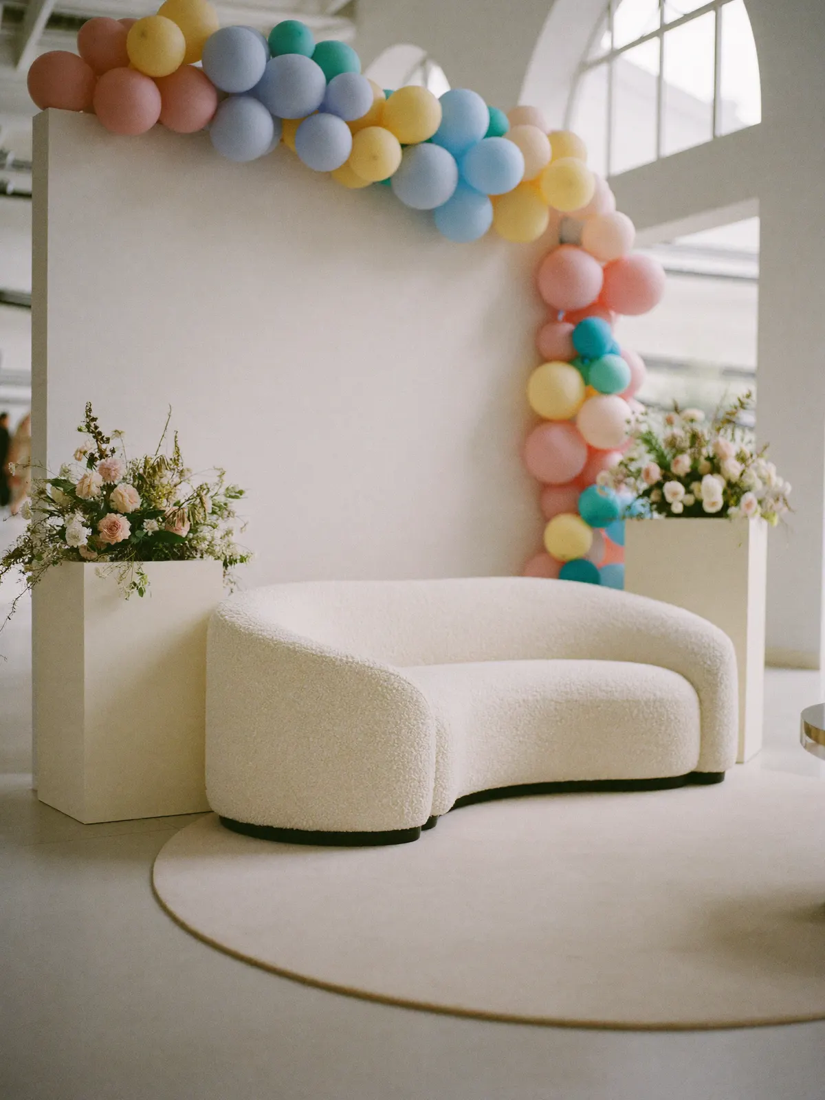 A styled lounge corner with a garland over an arched backdrop